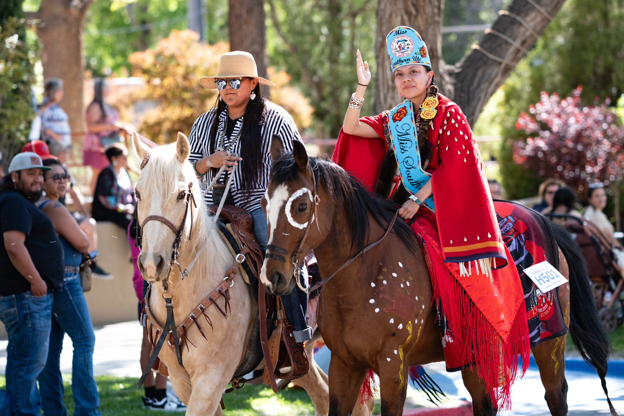 Miss Southern Ute, Maleina Carel rides in full regalia on a horse named “Gigi” during the annual Horse & Rider Parade, accompanied by equine handler, Tatum Bebo. The parade takes place outdoors at EXPO New Mexico each year as part of the Gathering of Nations Powwow. The event draws dozens of horses and riders in traditional Native regalia, showcasing horsemanship skills and elaborate beadwork.